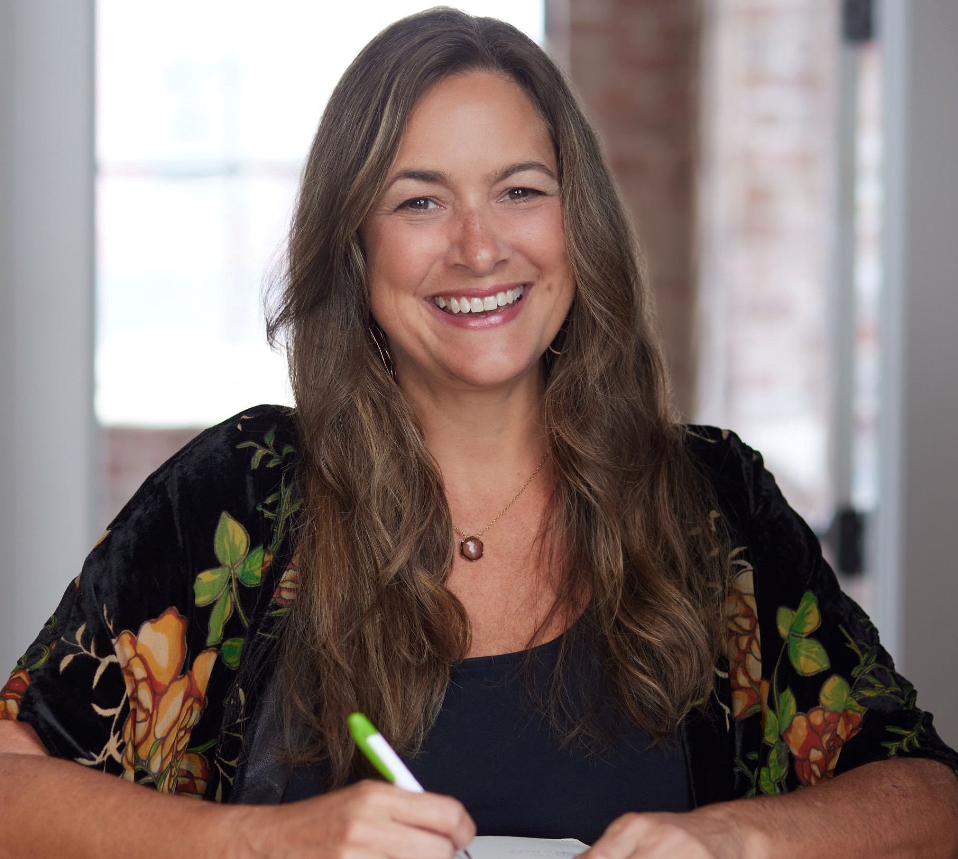 Portrait of Tamara V. Lucas in soft golden light surrounded by green foliage